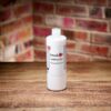Small bottle of Frenchic Finishing Coat displayed on a rustic wooden surface with a brick wall backdrop
