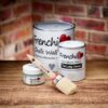 Frenchic Medium Oval Brush with red ferrule shown with Frenchic Al Fresco, Lazy Range, and Chalk Wall Paint tins on wooden surface