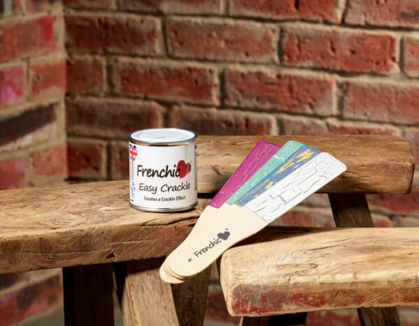 Frenchic Easy Crackle 250ml tin beside painted sample sticks showing crackle effects on rustic wooden bench
