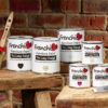 Stringers DIY Frenchic Furniture Paint cans on rustic wood with a paintbrush, against a brick wall background.