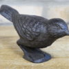 Cast iron bird sculpture with detailed feather texture, black finish, and standing on a wooden surface.