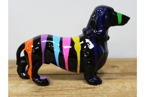 Decorative black dog figurine with colourful paint drips, on a wooden surface, for home decor or art display.
