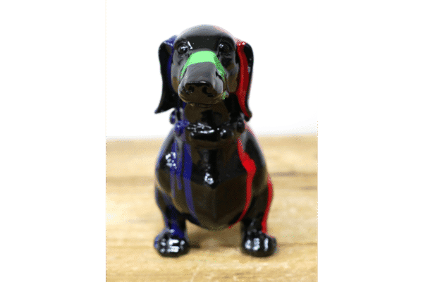 Colourful ceramic dog figurine with green, red, and blue accents on a wooden surface.