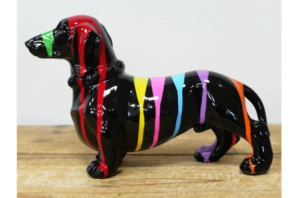 Colourful ceramic dachshund figurine with rainbow stripes on a wooden surface.
