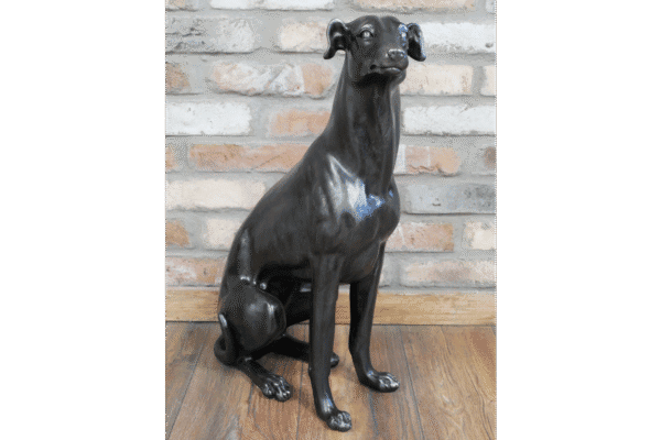 Decorative black dog sculpture sitting on a wooden floor against a brick wall at Stringers Home Decorating Centre.
