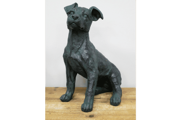 Bronze dog sculpture sitting on a wooden surface, detailed and artistic.