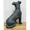 Bronze sculpture of a sitting dog with a textured surface, displayed on a wooden surface against a plain white background.