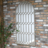 Large rustic mirror with geometric metal frame mounted on a brick wall in a home decor setting.