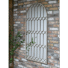 Large rustic mirror with a decorative metal frame mounted on a brick wall, ideal for home decorating.