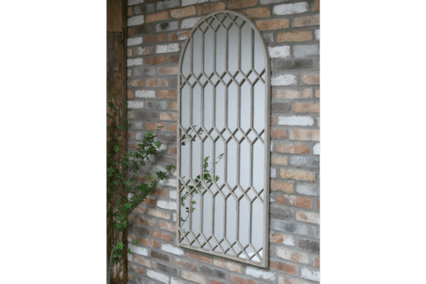 Large rustic mirror with a decorative metal frame mounted on a brick wall, ideal for home decorating.