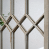 Close-up of a rustic wooden lattice panel with a brick wall in the background, suitable for home decor or garden features.