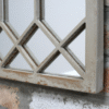 Close-up of a rustic metal window grille with a weathered finish, mounted on a brick wall.