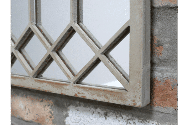 Close-up of a rustic metal window grille with a weathered finish, mounted on a brick wall.