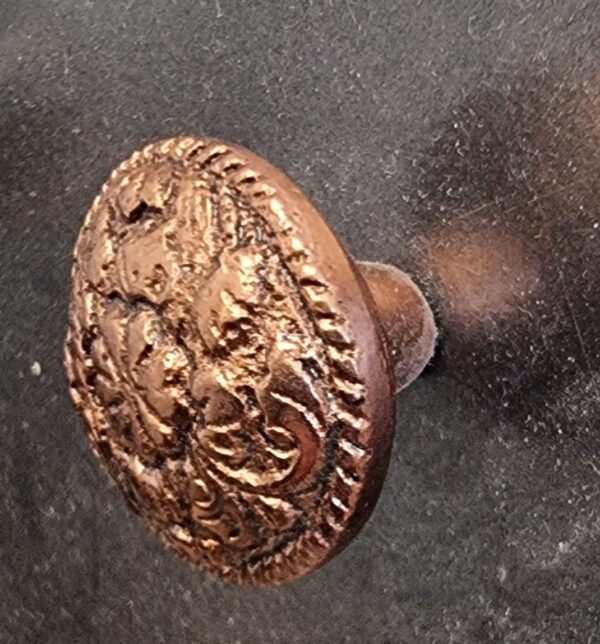 Close-up of a decorative round copper cabinet knob with intricate embossed design, suitable for home decorating projects.