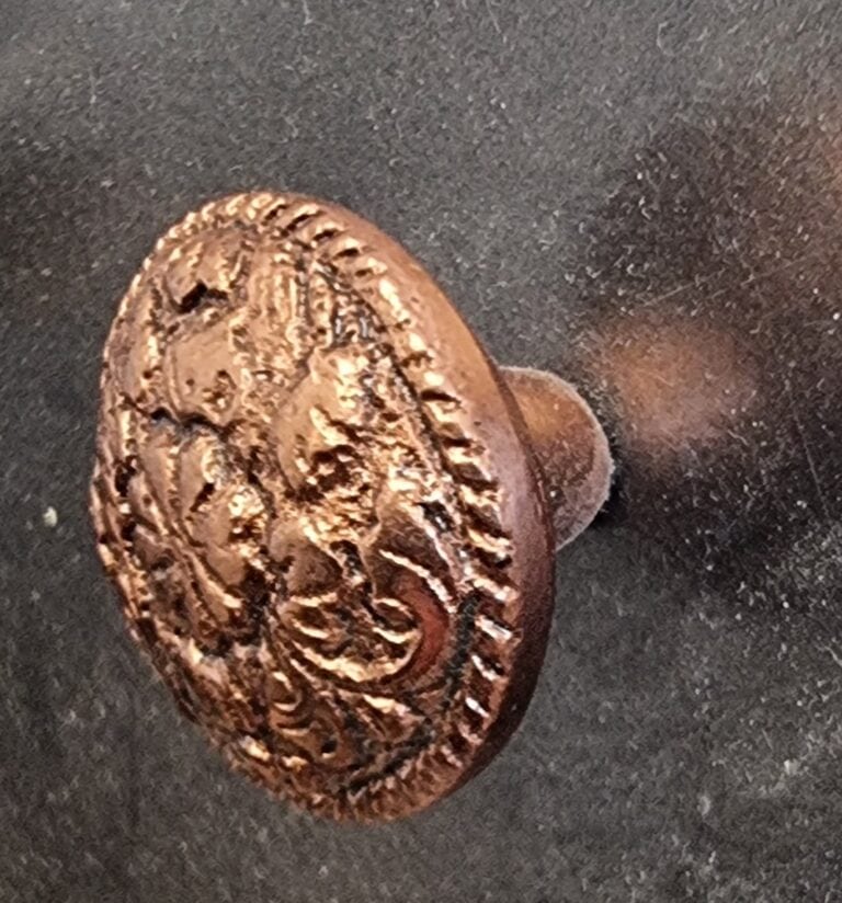 Close-up of a decorative round copper cabinet knob with intricate embossed design, suitable for home decorating projects.