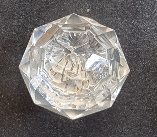Close-up of a cut glass globe with intricate facets, used as a decorative cabinet knob or handle.