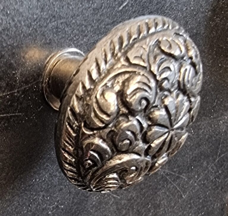 Decorative oval silver cabinet knob with intricate floral and scroll design, ideal for enhancing furniture with a vintage or classic style.