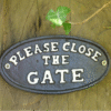 Please Close the Gate sign on wooden fence with green ivy leaf nearby, suitable for garden or outdoor decor.