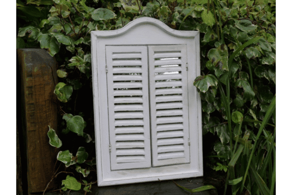 White shutter mirror with louvered shutters and decorative top, ideal for home decor and wall accents.