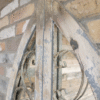 Close-up of a rustic, weathered wooden door with metal scrollwork, set against a brick wall, showcasing vintage charm and craftsmanship.