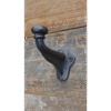 Industrial single coat hook mounted on a wooden wall, showcasing durable black metal design.