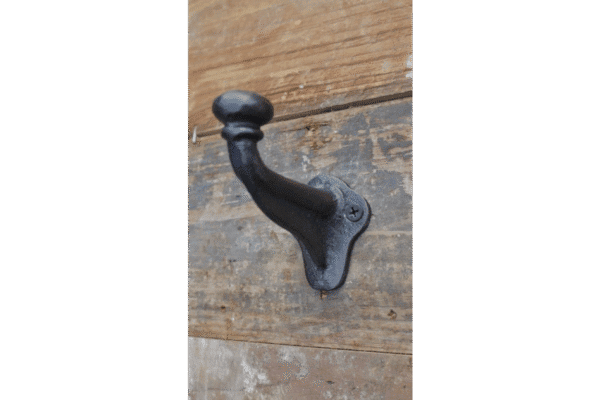 Industrial single coat hook mounted on a wooden wall, showcasing durable black metal design.