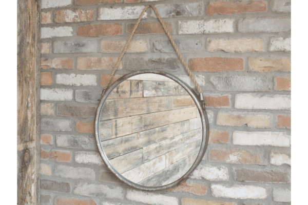 Industrial round metal and rope mirror hanging on a brick wall, suitable for home decorating.