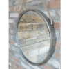 Industrial round metal and rope mirror hanging on a brick wall, suitable for modern home decor.