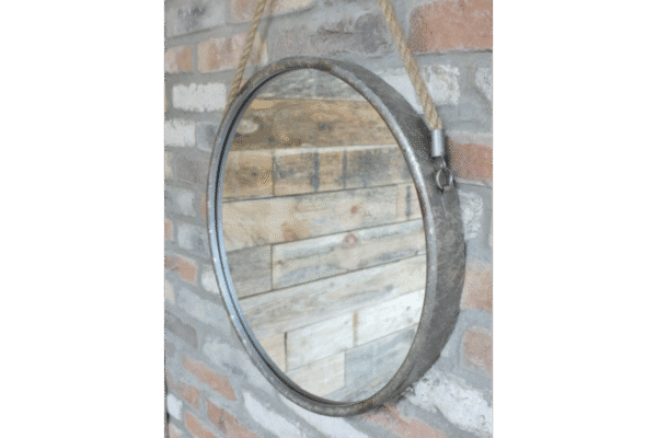 Industrial round metal and rope mirror hanging on a brick wall, suitable for modern home decor.