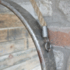 Close-up of a rustic industrial round mirror with a rope hanging mechanism against a brick wall.