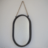 Black oval mirror with a rope hanger, suitable for modern home decor, displayed on a plain wall.