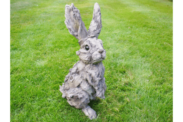 Large wood effect rabbit sculpture with detailed fur and tall ears, placed on a grassy lawn for outdoor decoration.