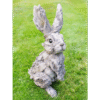 Large wooden rabbit sculpture with a textured, weathered finish, sitting on a grassy lawn, ideal for garden decor or outdoor decoration.