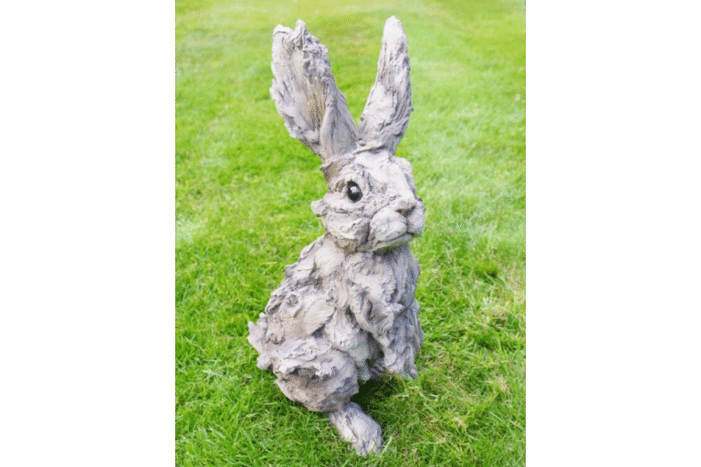 Large wooden rabbit sculpture with a textured, weathered finish, sitting on a grassy lawn, ideal for garden decor or outdoor decoration.
