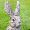 Large wooden rabbit sculpture with a textured, weathered finish, featuring tall ears and detailed facial features, set against a grassy background.
