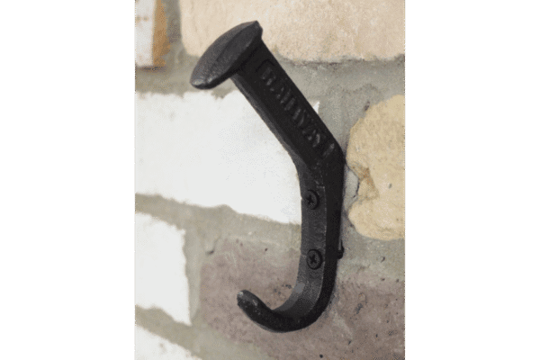 Close-up of a black railway pin coat hook mounted on a brick wall, used for hanging coats and accessories.