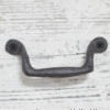 Wrought iron classic pull handle with black screws on a white wooden background, ideal for home decorating projects.