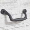 Wrought iron classic pull handle mounted on a white wooden surface, ideal for home decorating projects.