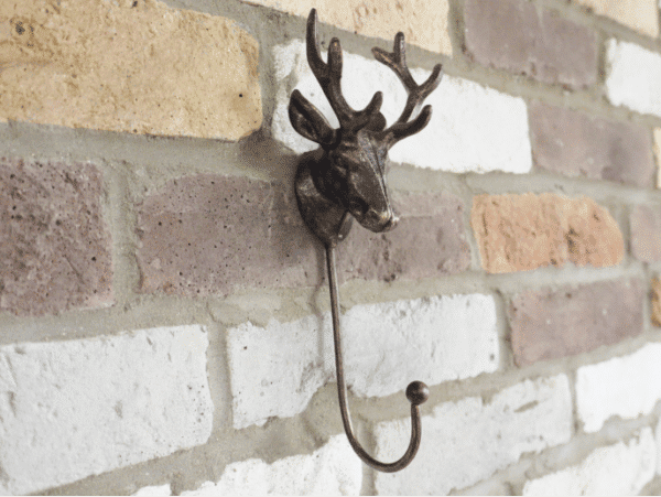 Decorative metal stag hook mounted on a brick wall, ideal for home decor and hanging items.