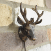Decorative metal stag head wall hook with antlers, mounted on a brick wall, ideal for home decor and hanging items.