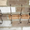 Decorative metal coat hooks mounted on a brick wall, ideal for home decor and organisation.