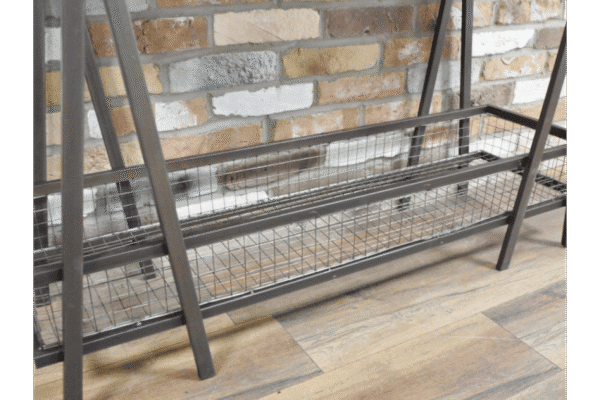 Industrial console table with metal frame and wire mesh shelf, set against a brick wall and wooden floor.