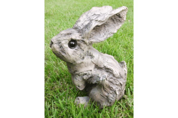 Decorative bunny sculpture made from wood effect material, placed outdoors on grass, suitable for home decorating projects.