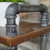 Industrial pipe shelf unit made from black metal pipes on a wooden surface, suitable for home decorating and storage solutions.