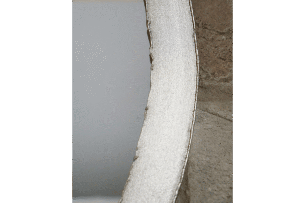 Close-up of a silver industrial round mirror with a textured frame, showcasing its reflective surface and modern design.