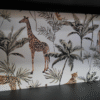 Decorative wallpaper featuring giraffes, leopards, and tropical plants in an exotic jungle theme.