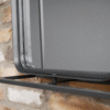 Close-up of a modern industrial wall unit with a mirror, mounted on a brick wall, showcasing sleek metal design and reflective surface.