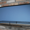 Modern black mirror with shelf mounted on a brick wall, ideal for home decor and storage solutions.