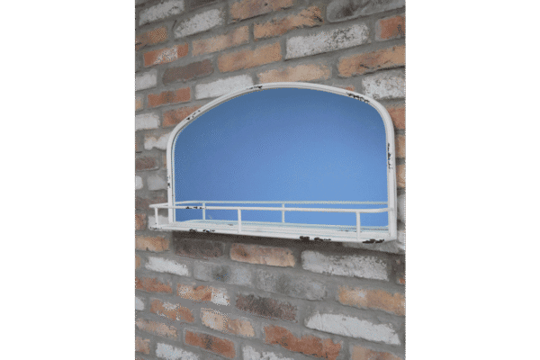 A vintage aged white mirror with a built-in shelf, mounted on a brick wall, ideal for home decor and wall accents.