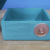 Blue vintage gramophone storage box with a round metallic knob on the front, placed on a wooden surface.